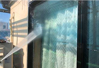 窓を高圧洗浄する様子