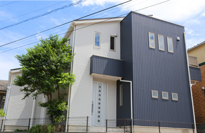 外壁塗装が完了し、ベージュとブルーグレーのツートンカラーの戸建に美しく仕上がりました